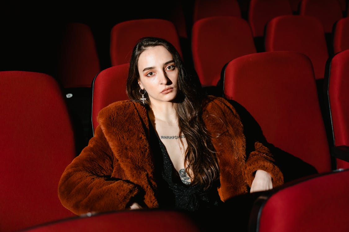 A Woman Sitting on a Red Chair in a Cinema