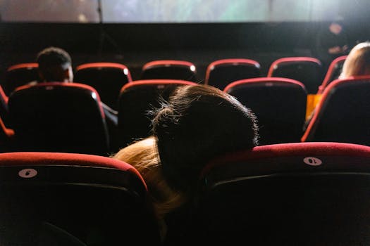 A couple enjoying a movie night in a cozy cinema setting with plush red seats.