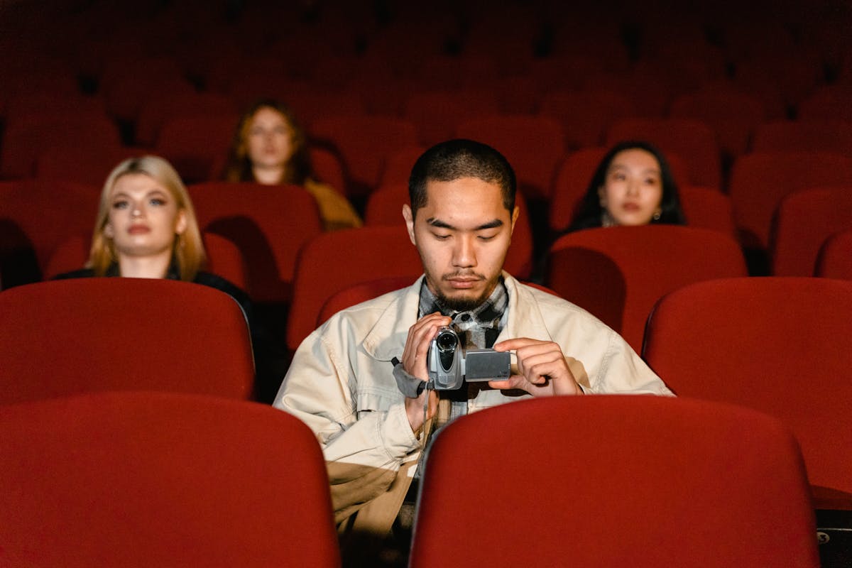 Audience watching a film in a cinema, silhouetted by screen light