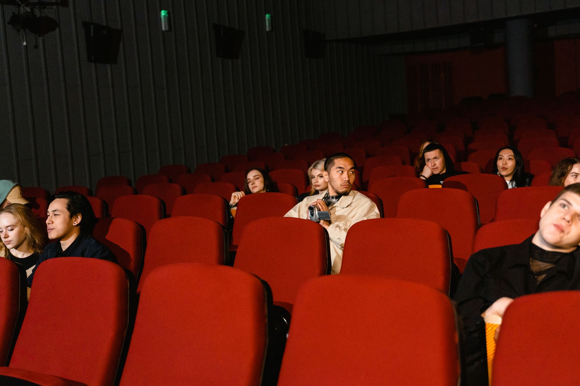 Group of people watching a film in a sparsely populated cinema theater.