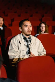 Adult man sitting in a cinema watching a film with others.