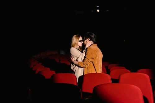 Free A romantic couple wearing 3D glasses embracing in an empty movie theater. Stock Photo