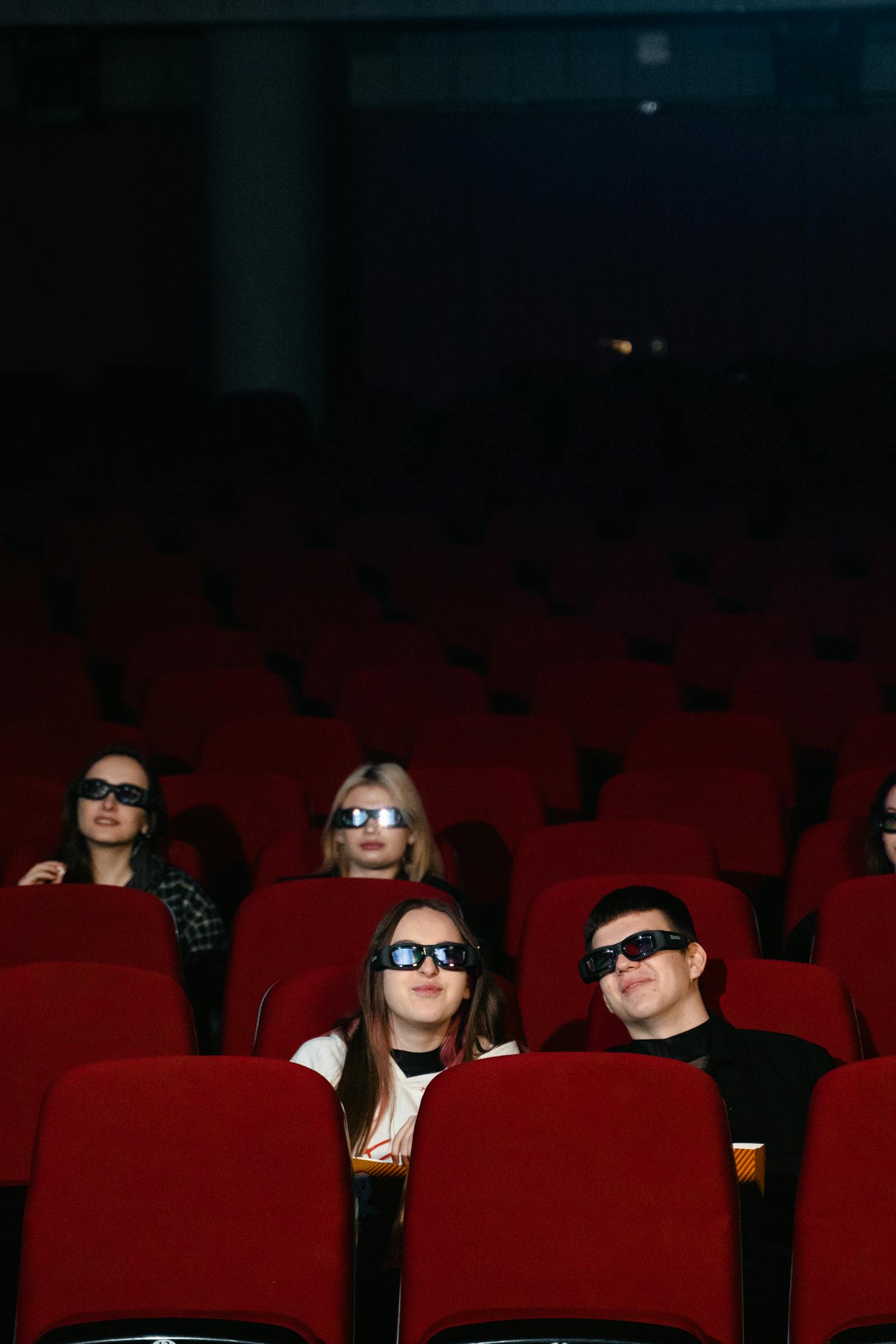 Audience seats in a dimly lit movie theater representing theatrical box office attendance