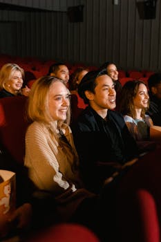 A diverse group of friends enjoying a movie at the cinema, with smiles and popcorn.