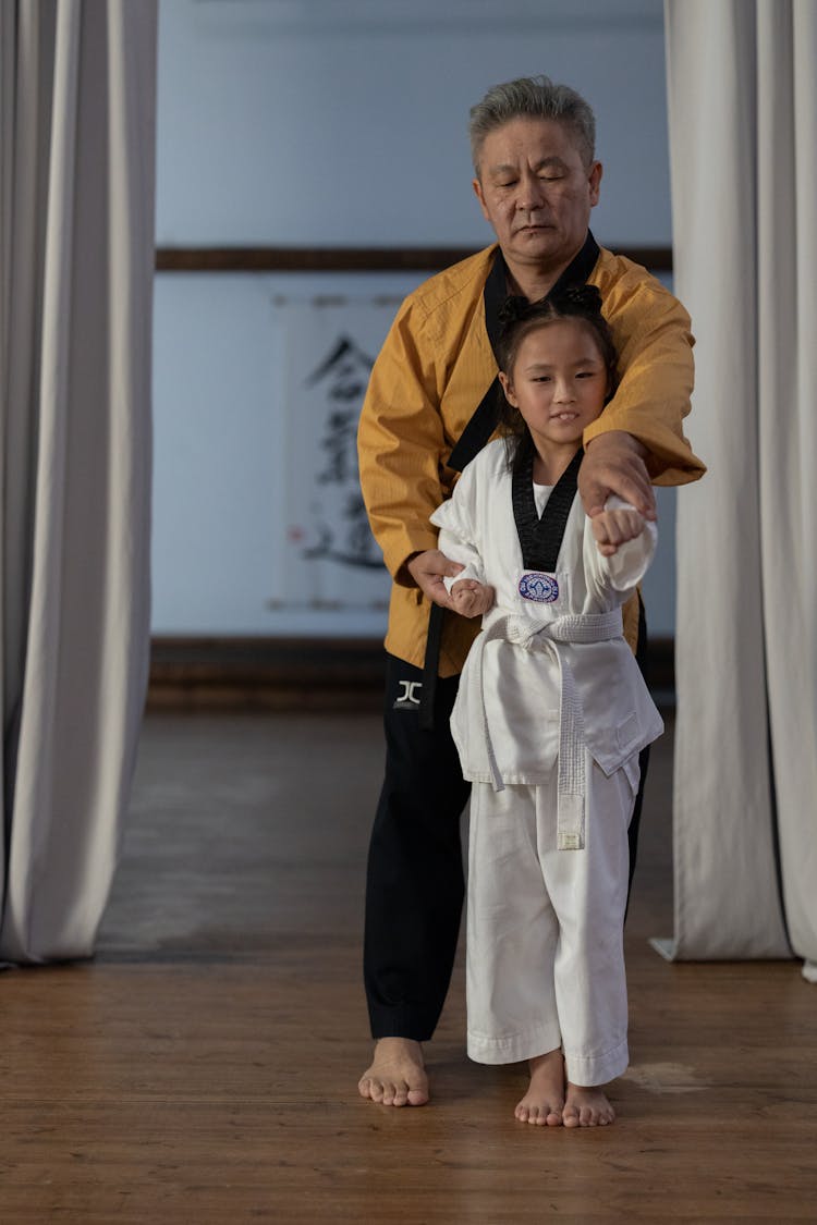 A Karate Teacher Holding A Child With Clenched Fists