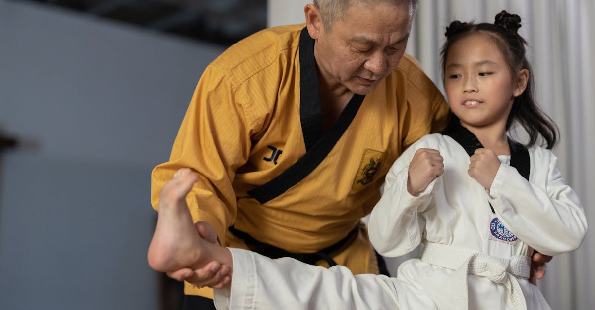 An instructor guiding a young girl in martial arts training indoors.