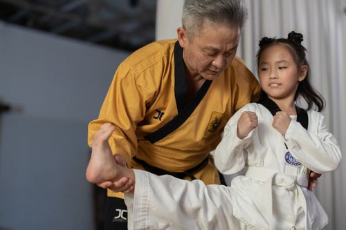 Free An instructor guiding a young girl in martial arts training indoors. Stock Photo