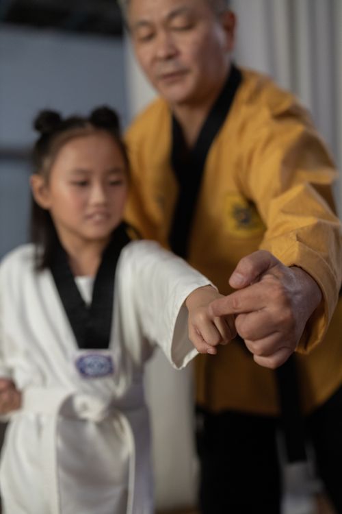 Free A martial arts instructor helps a young student with her karate stance in class. Stock Photo