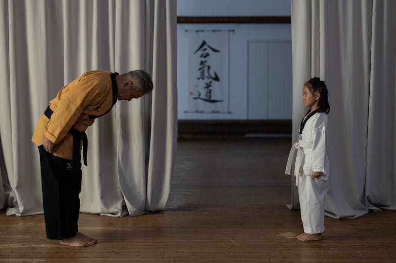 Martial arts instructor demonstrating traditional respect and bowing technique to student in dojo
