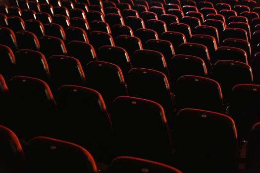A view of empty red theater seats lit softly, showcasing the quiet ambiance of a cinema.