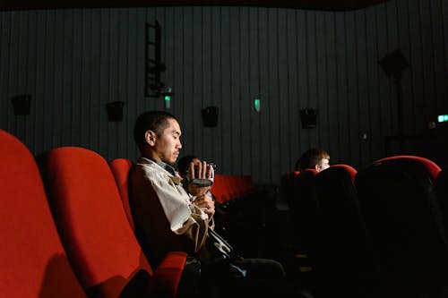 A Man Sitting on the Cinema Holding a Video Recorder