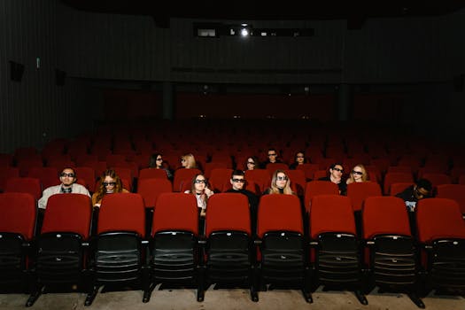 People watching a movie wearing 3D glasses in a near-empty cinema hall.