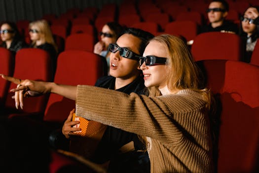 A couple wearing 3D glasses enjoy a movie at a theater, immersed in the experience.
