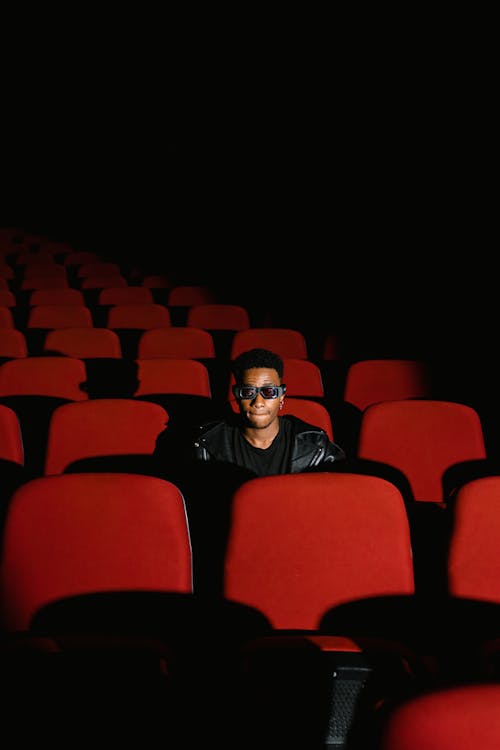 A Man in Black Shirt Sitting Inside the Cinema