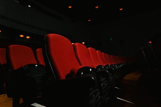 A close-up of empty red seats in a dark movie theater, emphasizing solitude and anticipation.