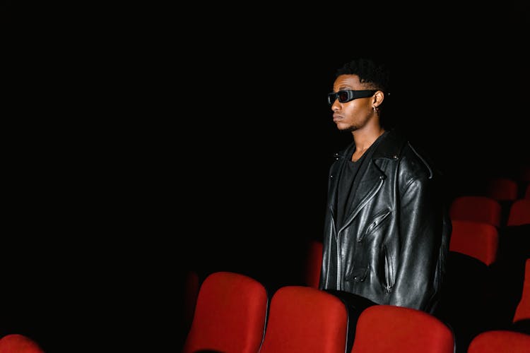 A Man In Black Leather Jacket Wearing Sunglasses Inside The Cinema