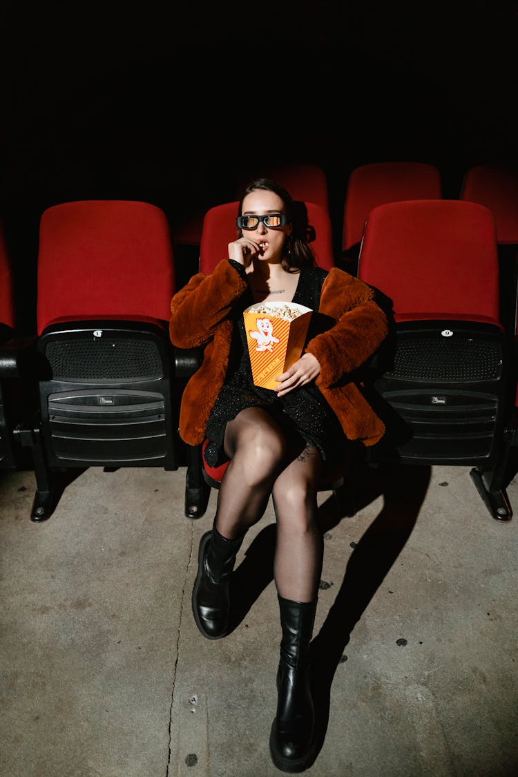A Woman Watching A Movie Eating Popcorn