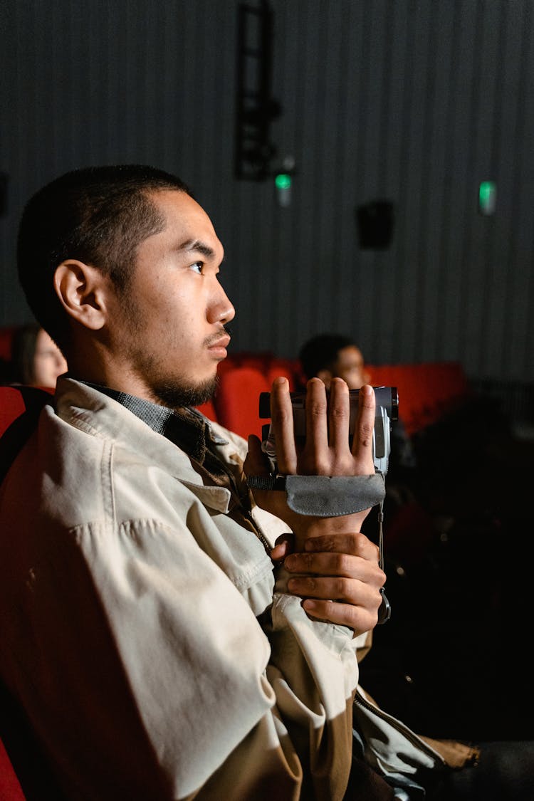 A Man Watching A Movie Holding A Video Camera