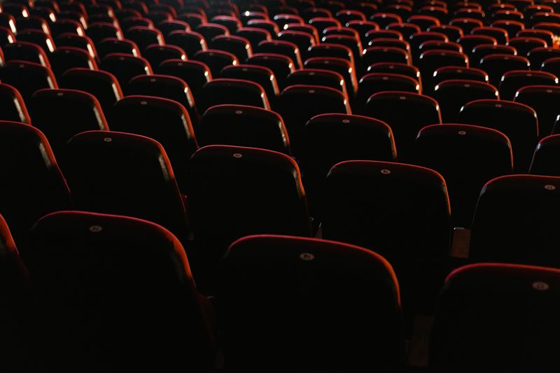 Rows of empty red seats in a dimly lit movie theater, showcasing a cinema environment.