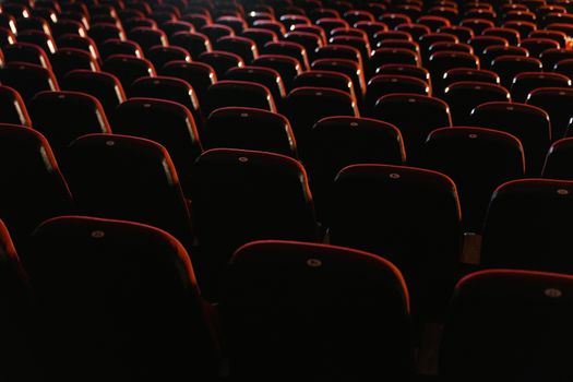 Rows of empty red seats in a dimly lit movie theater, showcasing a cinema environment.