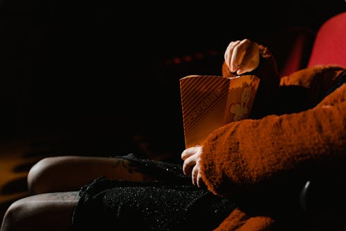 A Moviegoer Eating Popcorn Inside a Cinema