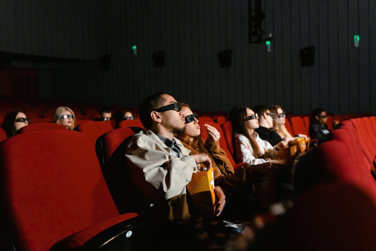 Movie theater audience watching a film with the screen glowing in the dark