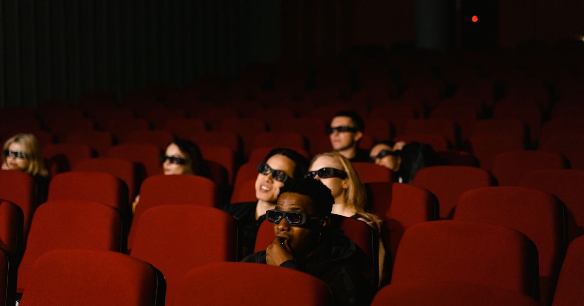 A diverse group of people wearing 3D glasses watching a movie in a theater.