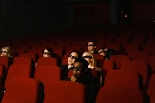 A diverse group of people wearing 3D glasses watching a movie in a theater.