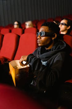 A person watching a 3D movie while eating popcorn in a cinema.
