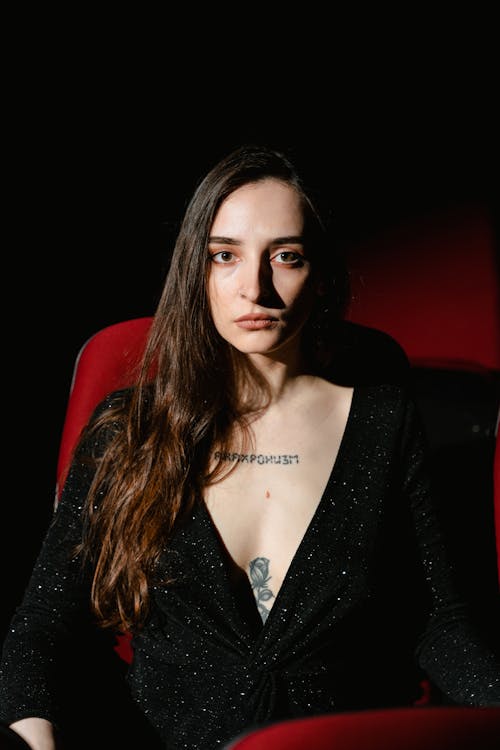 A Woman in Black Dress Sitting on a Red Chair