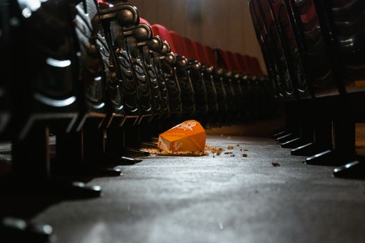 Empty movie theater aisle with spilled popcorn creating a messy scene.