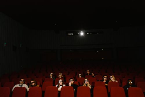 Free A group of people in a cinema watching a 3D movie wearing glasses, sitting in a dark theater. Stock Photo