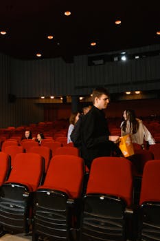 People interacting in a movie theater with red seats, creating a cozy atmosphere.
