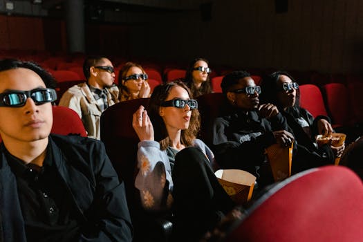 Audience wearing 3D glasses enjoying a movie in a cinema with popcorn.