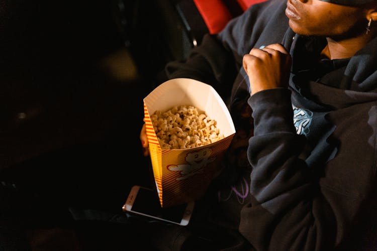 A Man Holding A Yellow Popcorn Box