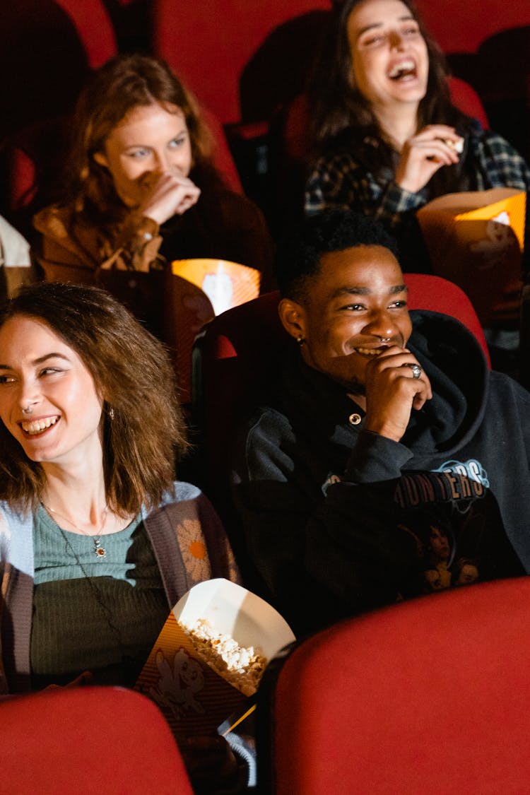 People Watching Movie While Holding Buckets Of Popcorn