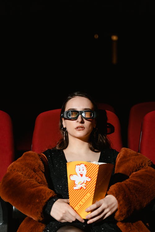 A Woman Sitting with Popcorn in a Movie Theater
