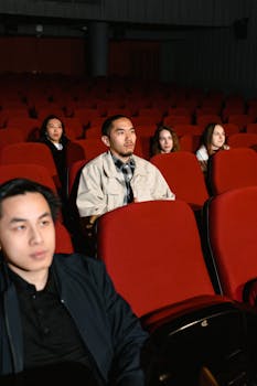 Group of diverse individuals enjoying a movie in a cinema with red seats.