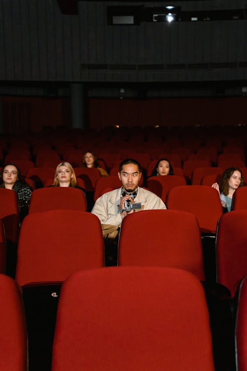 Multiracial People Sitting on Red Theater Seats