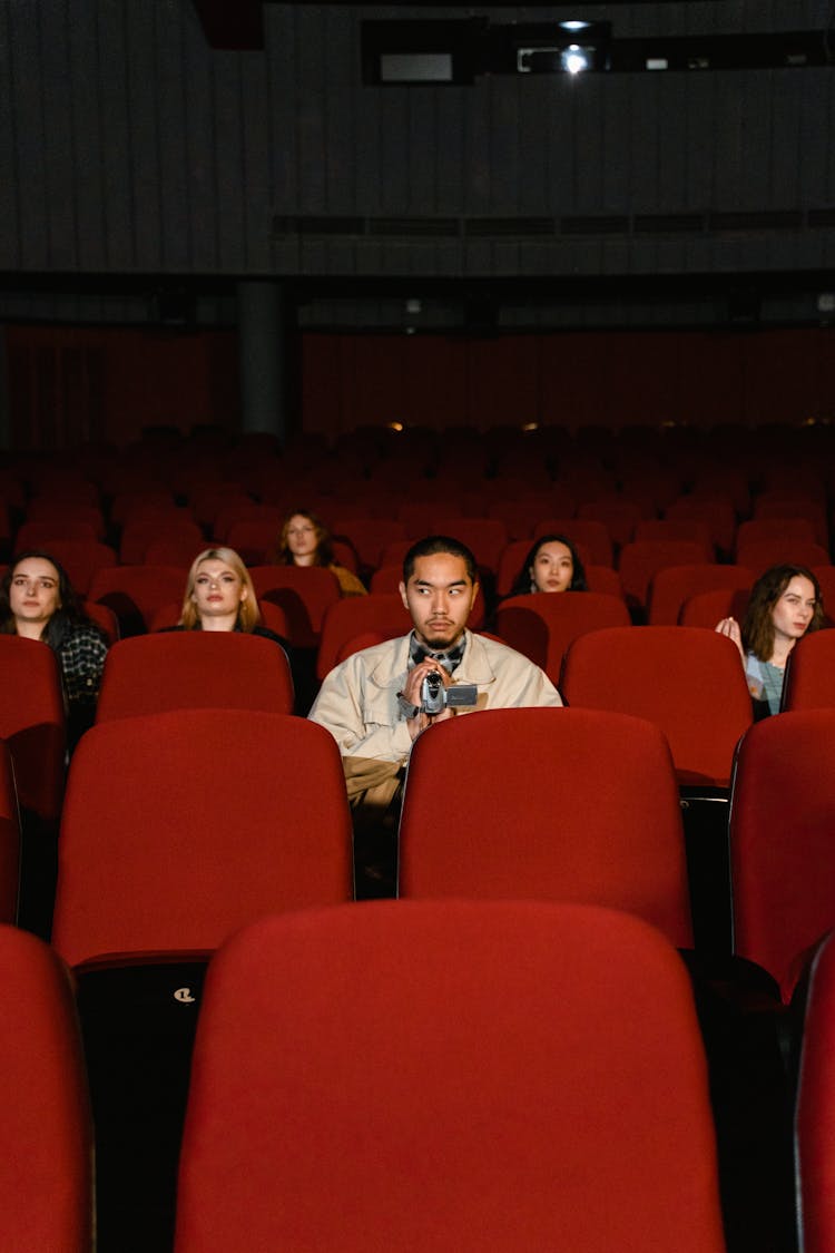 Multiracial People Sitting On Red Theater Seats