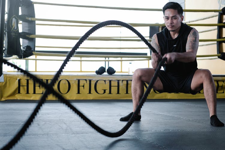 Determined Latin American Man Exercising With Ropes