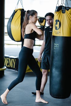 Female athlete practicing boxing with coach guidance indoors for fitness motivation.