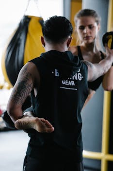 Two adults engaging in kickboxing training in a gym environment, showcasing action and focus.