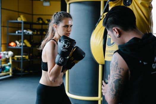 A determined female boxer trains with her coach in a gym, focusing on improving her punching skills.