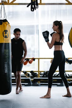 Female boxer practicing with personal trainer in modern gym.