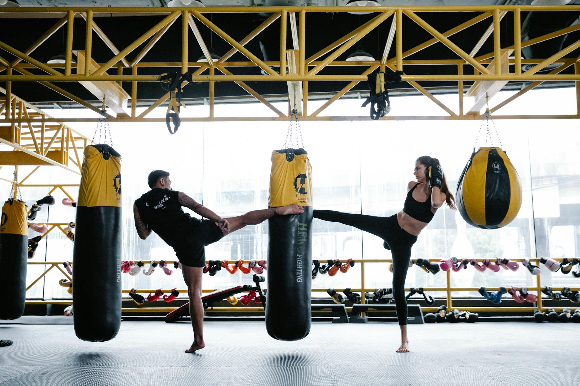 Fit young male and female athletes training on punching bag in gym