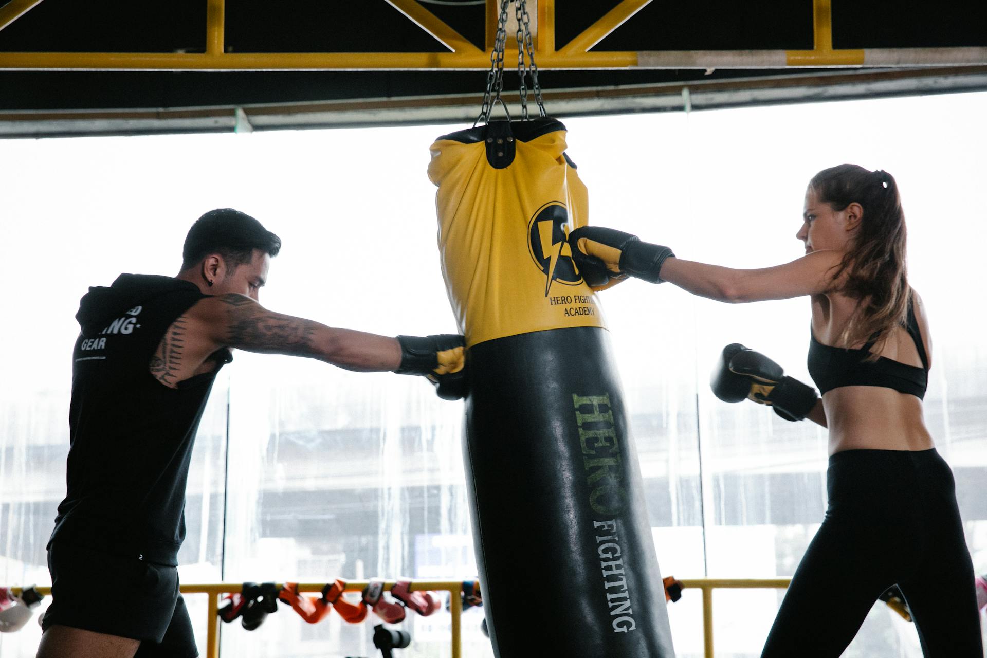 Powerful young male and female fighters boxing in club with punching bag