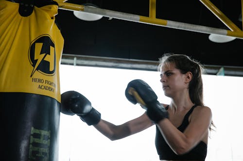 Strong fit woman doing boxing punches on bag in gym