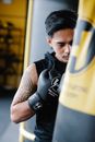 Brutal ethnic sportsman punching bag in boxing club