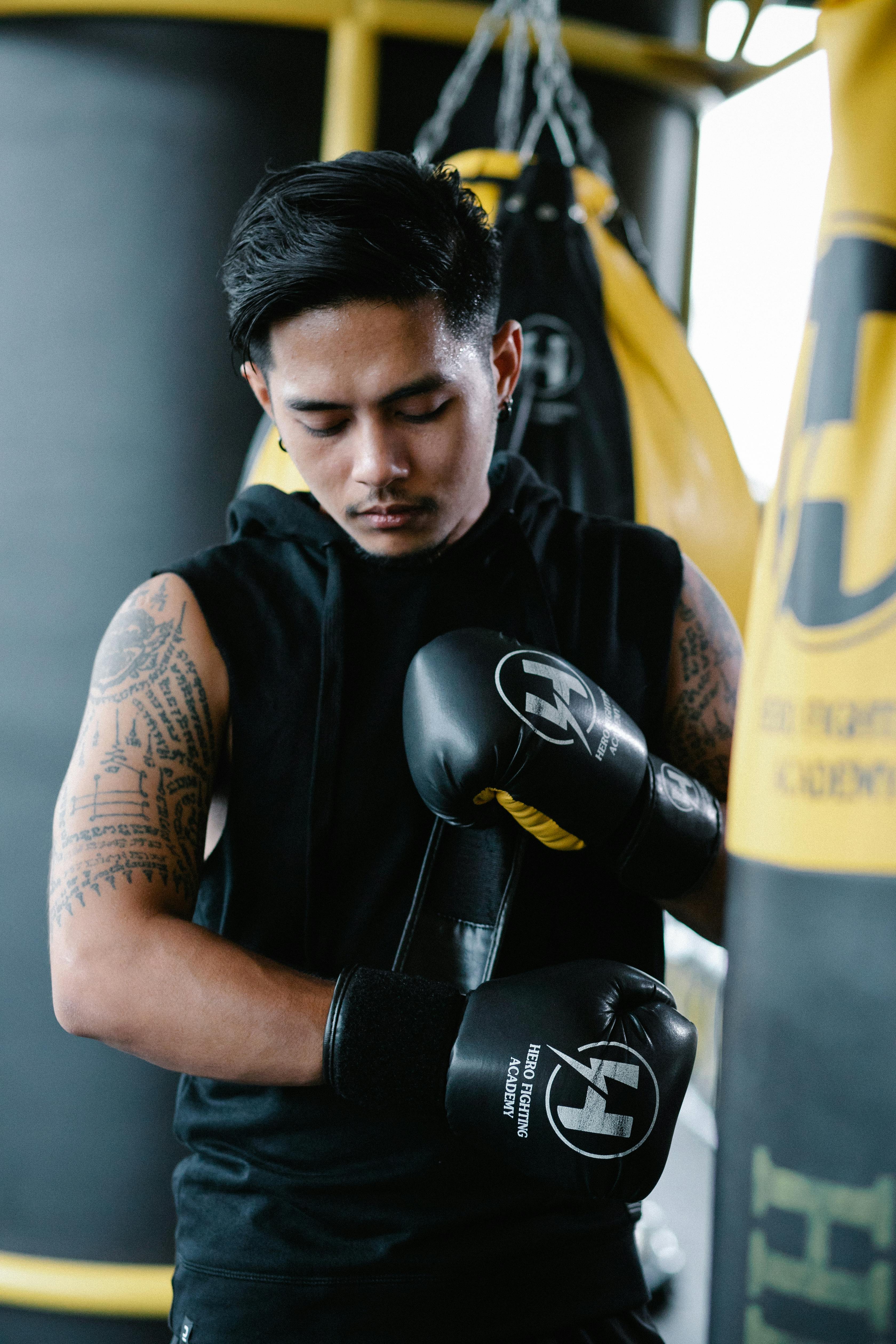 Ethnic boxer focusing while adjusting gloves · Free Stock Photo